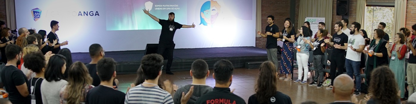 Allan on stage with arms open, facilitating a body percussion workshop with 100+ participants at a large corporate event